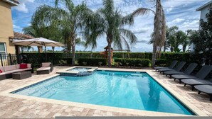 Una piscina rectangular con un jacuzzi, rodeada de sillones y un sofá.