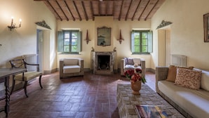 A spacious living room with a fireplace, wooden beams, and comfortable seating. - Villa Iside 8, Emma Villas (Peccioli)