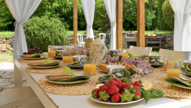 An outdoor breakfast setup with a table set for two, featuring plates of strawberries, juice, and pastries. - Villa Iside 8, Emma Villas (Peccioli)
