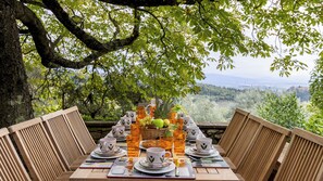 Une table dressée pour un repas, offrant une vue panoramique, entourée de chaises en bois.