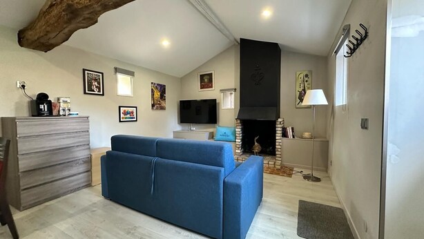 Un salon avec un canapé bleu, une commode en bois, un téléviseur à écran plat et une cheminée.