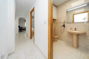 Une salle de bain avec un lavabo, un miroir et des toilettes.