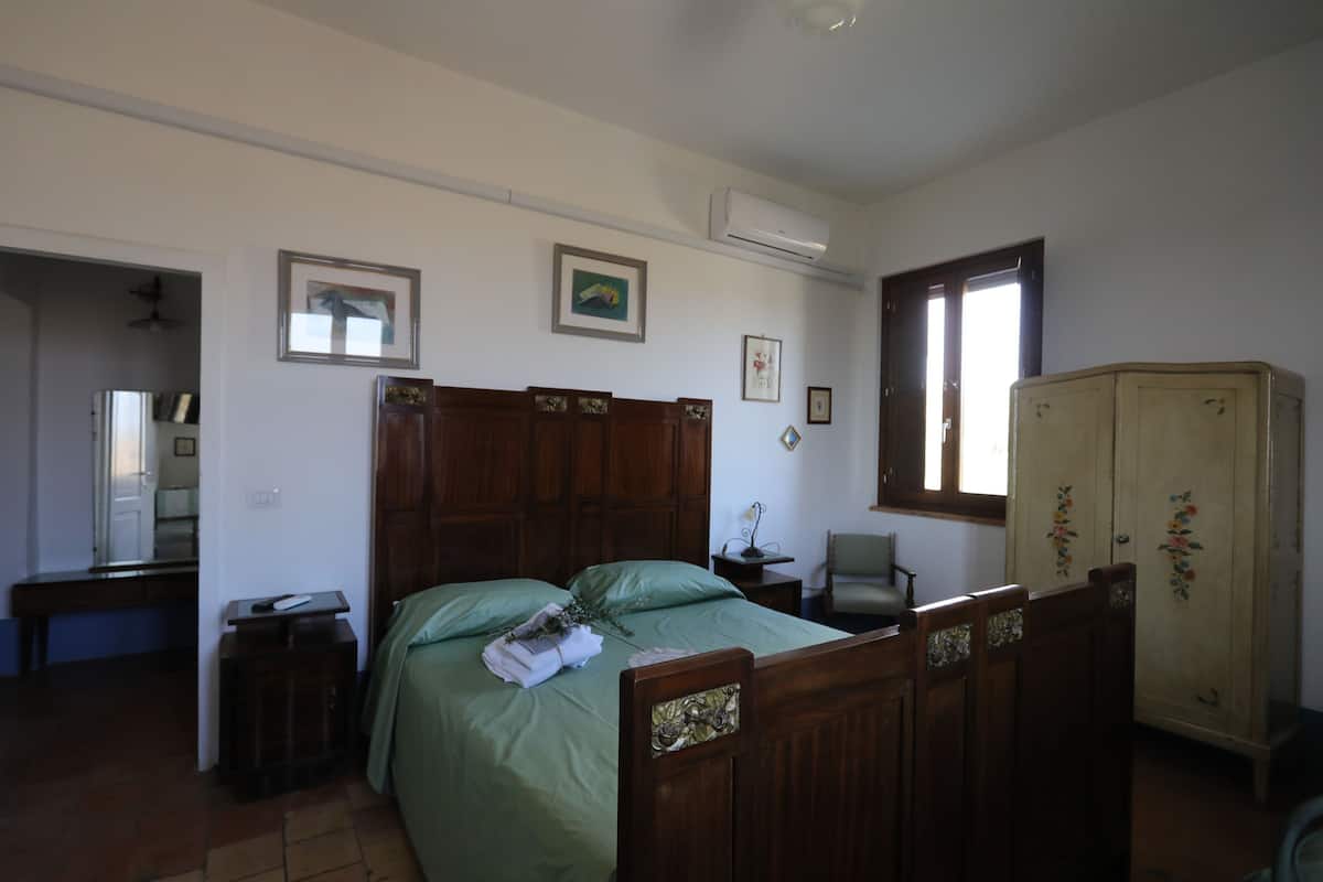 A bedroom with a wooden bed, a wardrobe, a desk, and a chair.