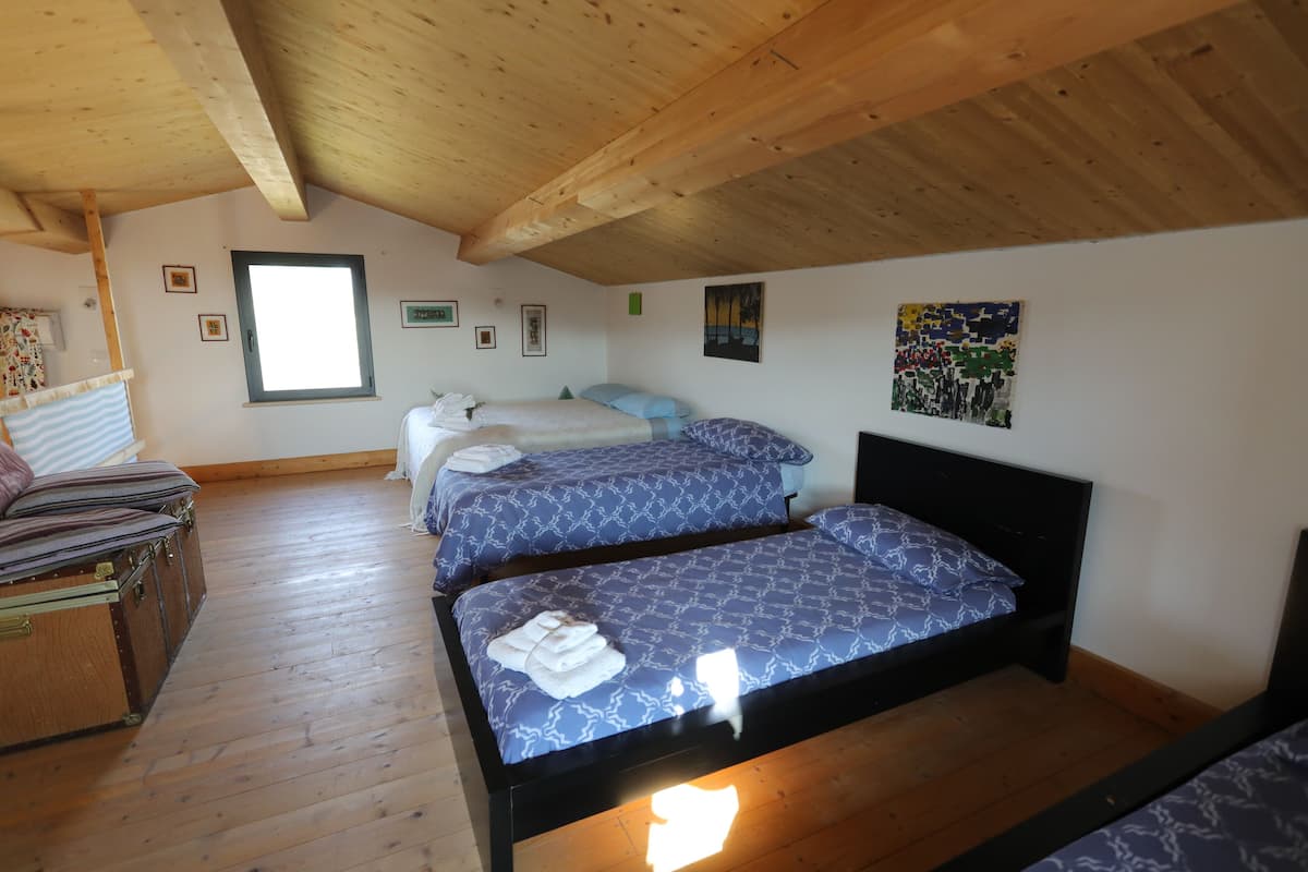 A room with two beds, wooden flooring, a window, and various wall decorations.