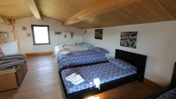 A room with two beds, wooden flooring, a window, and various wall decorations.