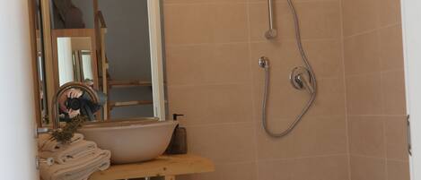 A bathroom with a sink, mirror, and shower.