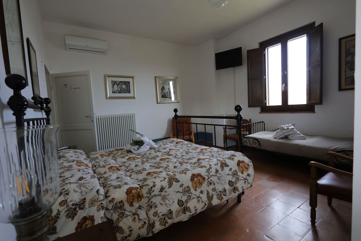 Une chambre à coucher avec un lit, une chaise, une fenêtre et un radiateur.