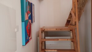 Ein Zimmer mit einer Holztreppe, einer weißen Wand und einem farbenfrohen, abstrakten Gemälde.