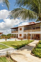 Um edifício de dois andares com piscina, área de estar externa e jardim.