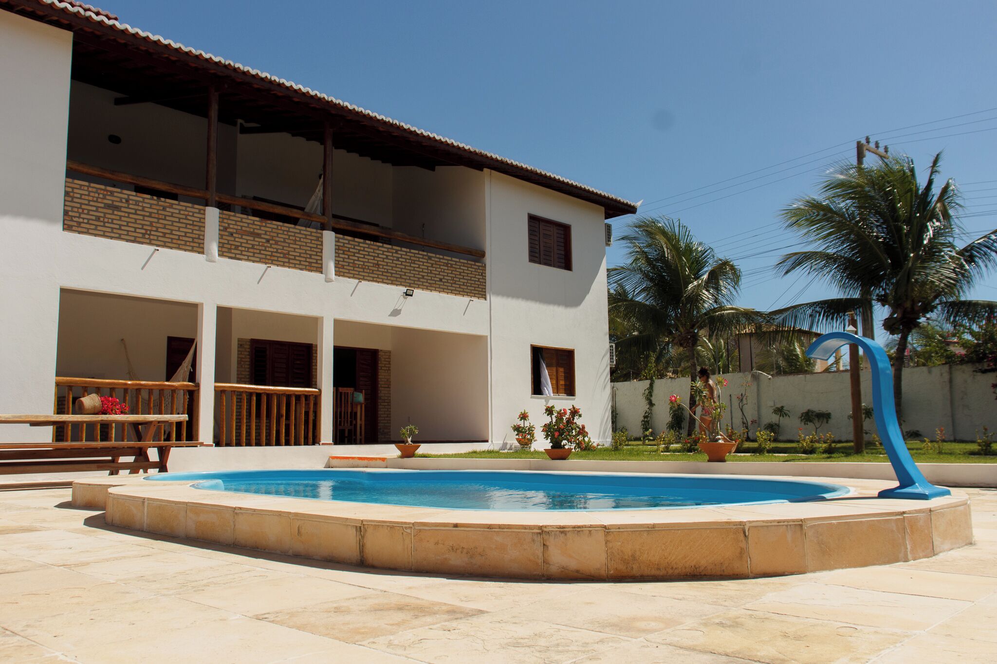 Une maison à deux étages avec une piscine, du mobilier d’extérieur et des plantes en pot.