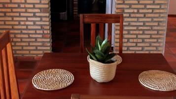 Un comedor con pared de ladrillo, mesa de madera, sillas y una planta en maceta.
