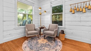 A cozy room with white wooden walls, two armchairs, a round rug, a floor lamp, and a wall-mounted bell arrangement. - ONLY 4 BLOCKs to Magnolia-Hot tub-Texas Bell in Waco (Waco)