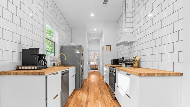 A narrow kitchen with white cabinets, a wooden countertop, a coffee maker, and a refrigerator. - ONLY 4 BLOCKs to Magnolia-Hot tub-Texas Bell in Waco (Waco)