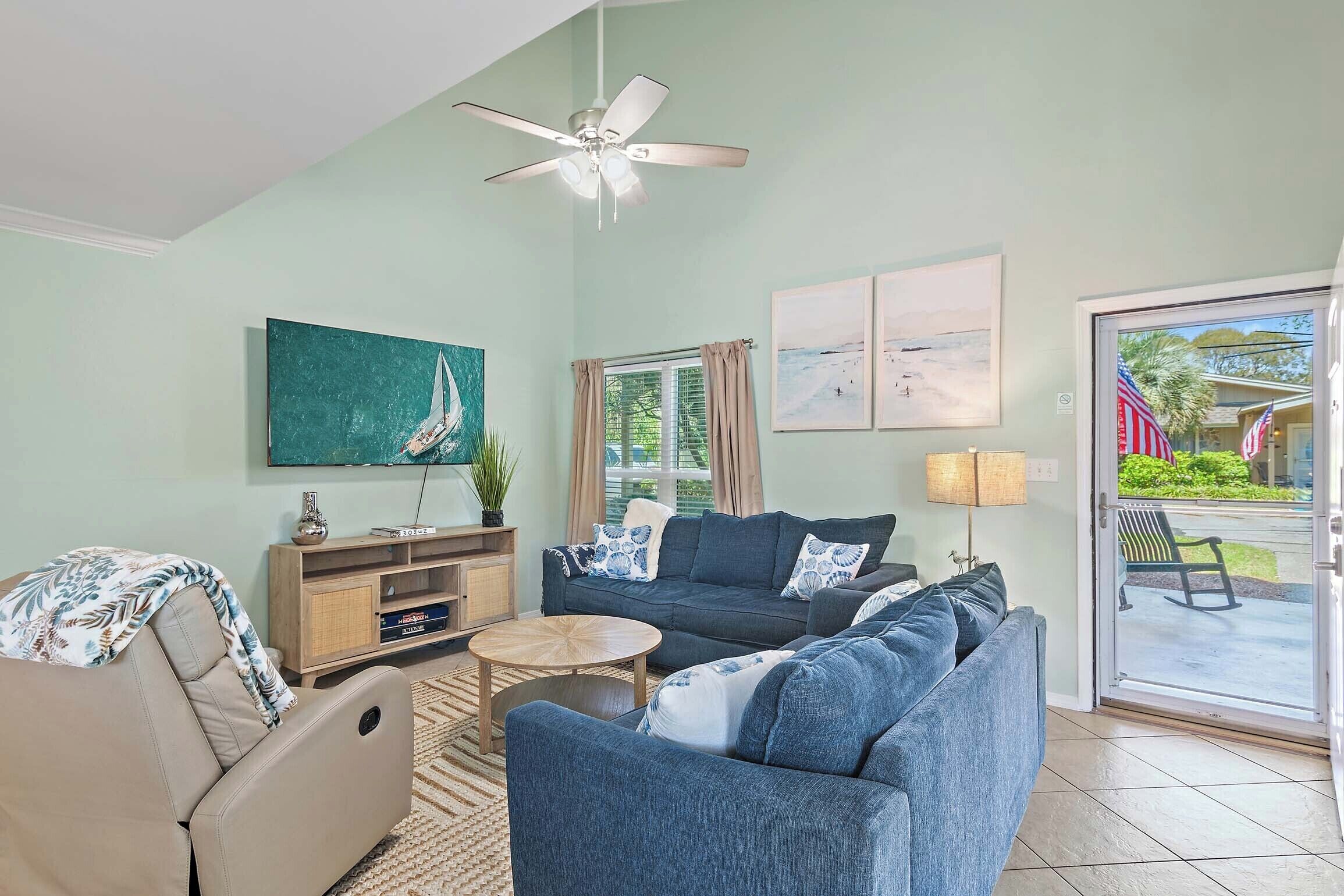 A living room with a sofa, a coffee table, a TV, and a ceiling fan.