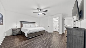 Un dormitorio con cama, mesitas de noche, ventilador de techo, cómoda y estantes empotrados.
