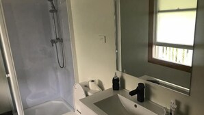 Ein Badezimmer mit Dusche, Toilette, Waschbecken und Spiegel.