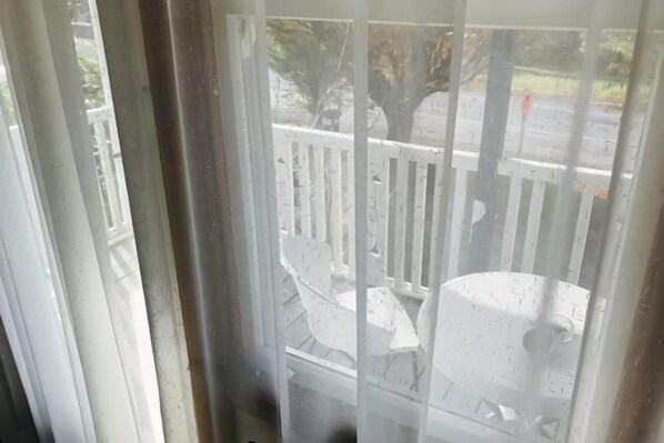 A view through a window with a white railing, a white chair, and a white structure. - Te Puia Hot Springs Hotel (Te Puia Springs)