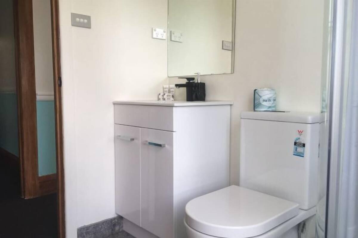 A small, clean bathroom with a white toilet, a white sink, and a mirror above the sink.