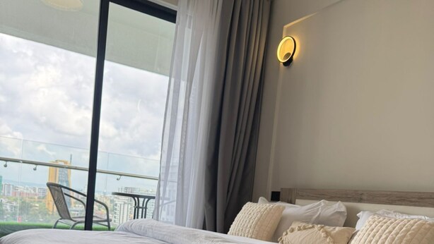 Et moderne hotelværelse med en stor seng, en balkon med byudsigt og et bybillede til syne gennem vinduet.