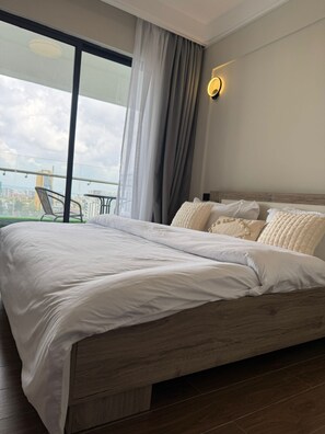 A modern hotel room with a large bed, a balcony with a view of the city, and a cityscape visible through the window. - Lux Suites Capital Rise Apartments (Nairobi)