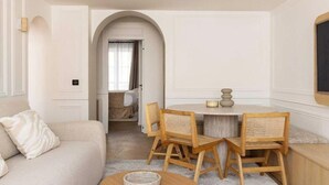 Una habitación con un sofá, una mesa de comedor con sillas y una mesa redonda pequeña con un tazón.