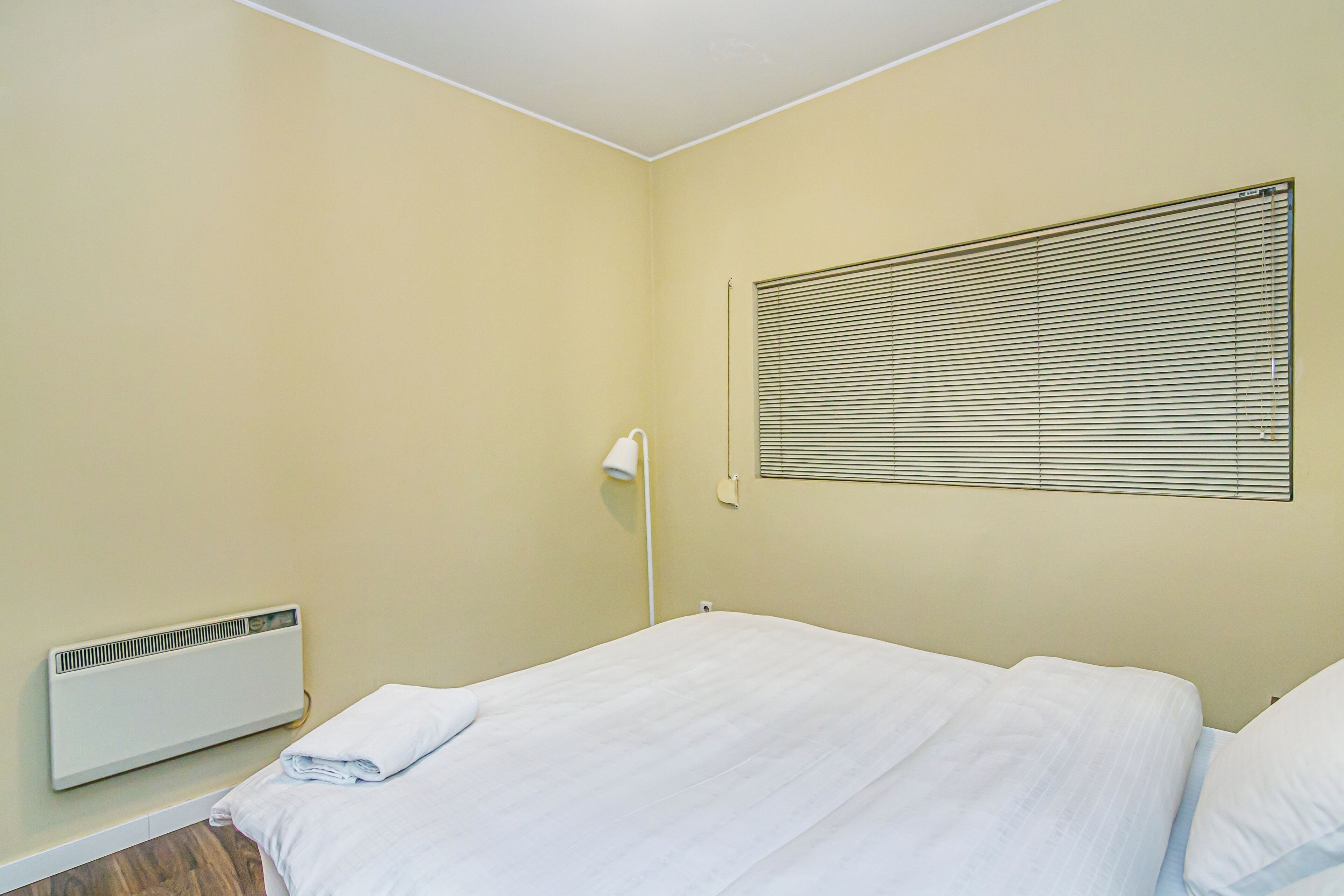 Ein Zimmer mit einem Bett, einem Heizkörper und einem Fenster mit Jalousien.