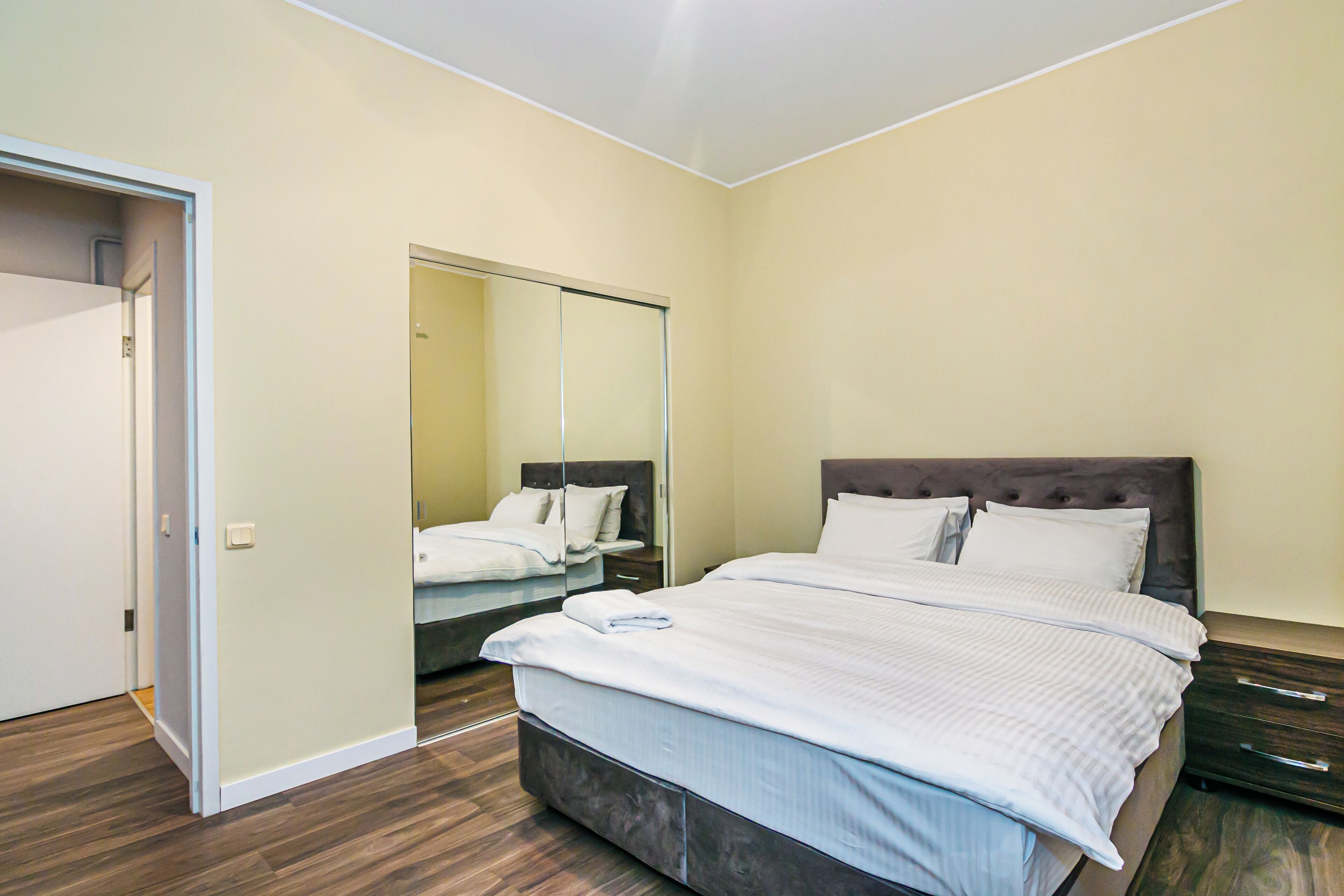 A bedroom with a large bed, a mirror, and a wardrobe.