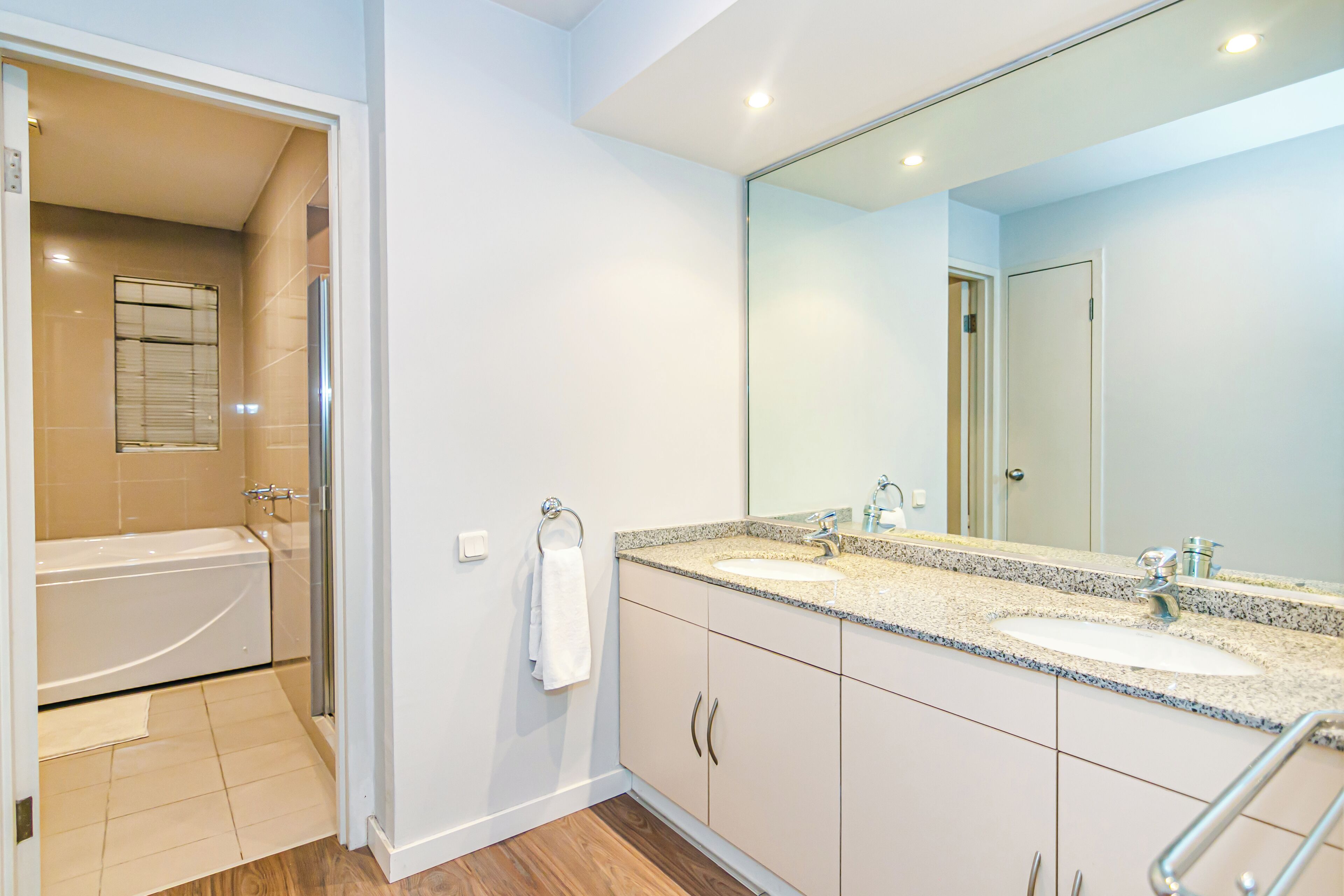 Une salle de bain moderne avec deux lavabos, un grand miroir et une baignoire.