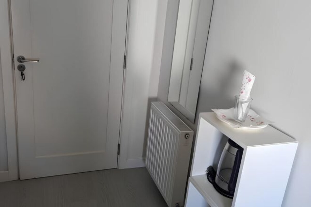 A room with a closed door, a radiator, and a microwave on a white cabinet.