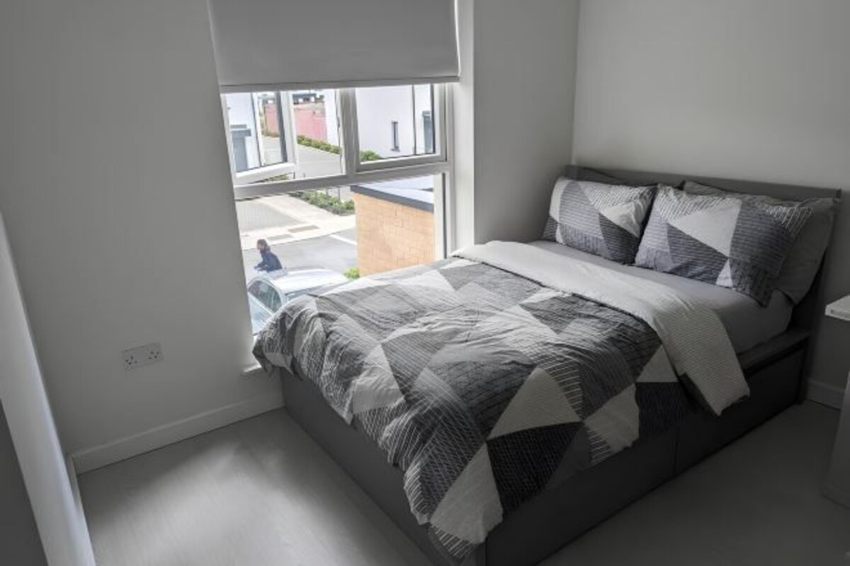 A bedroom with a bed, a window, and a view of the outside.