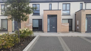 A modern building with a brick facade, large windows, and a gated entrance.