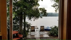 Een houten terras met twee ligstoelen gericht op een meer.