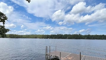 A wooden dock extending into a calm lake with a forested shoreline in the background.