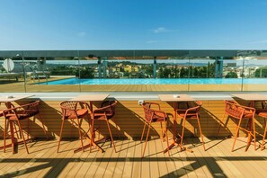 A rooftop pool area with wooden flooring, orange chairs, and tables, overlooking a cityscape. - The Social Hub Florence Belfiore (Florence)
