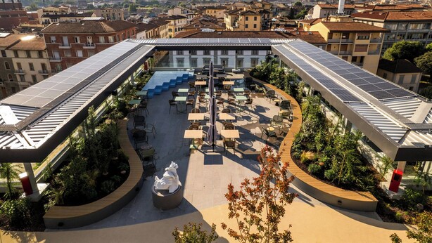 Terraza en la azotea con paneles solares, mobiliario exterior y una escultura central.