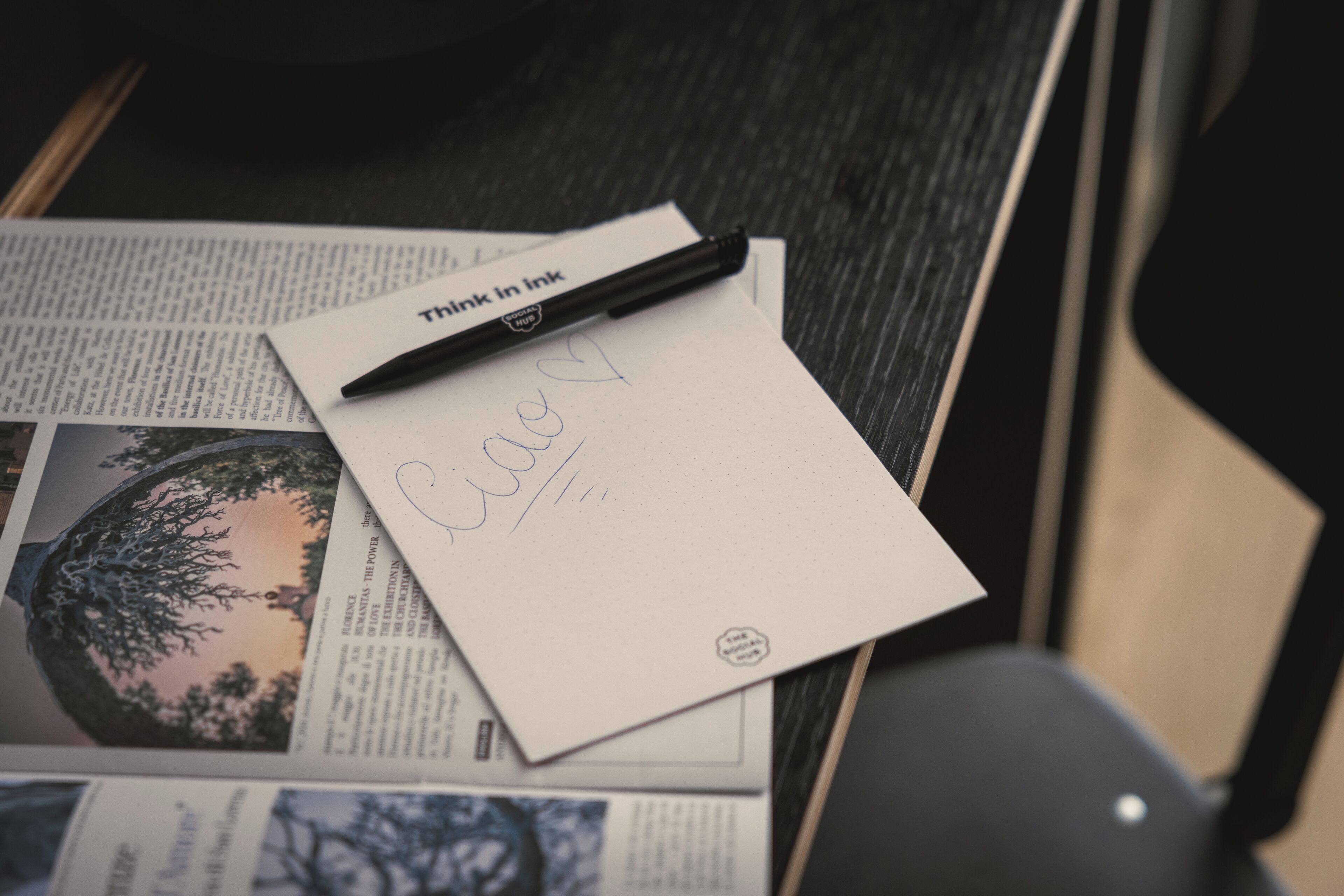 Un escritorio con una libreta, un bolígrafo y un periódico.