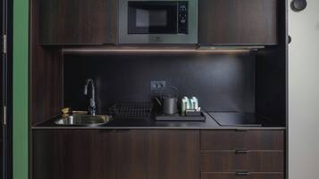 Une cuisine compacte équipée d’un micro-ondes encastré, d’un évier et d’un petit plan de travail.