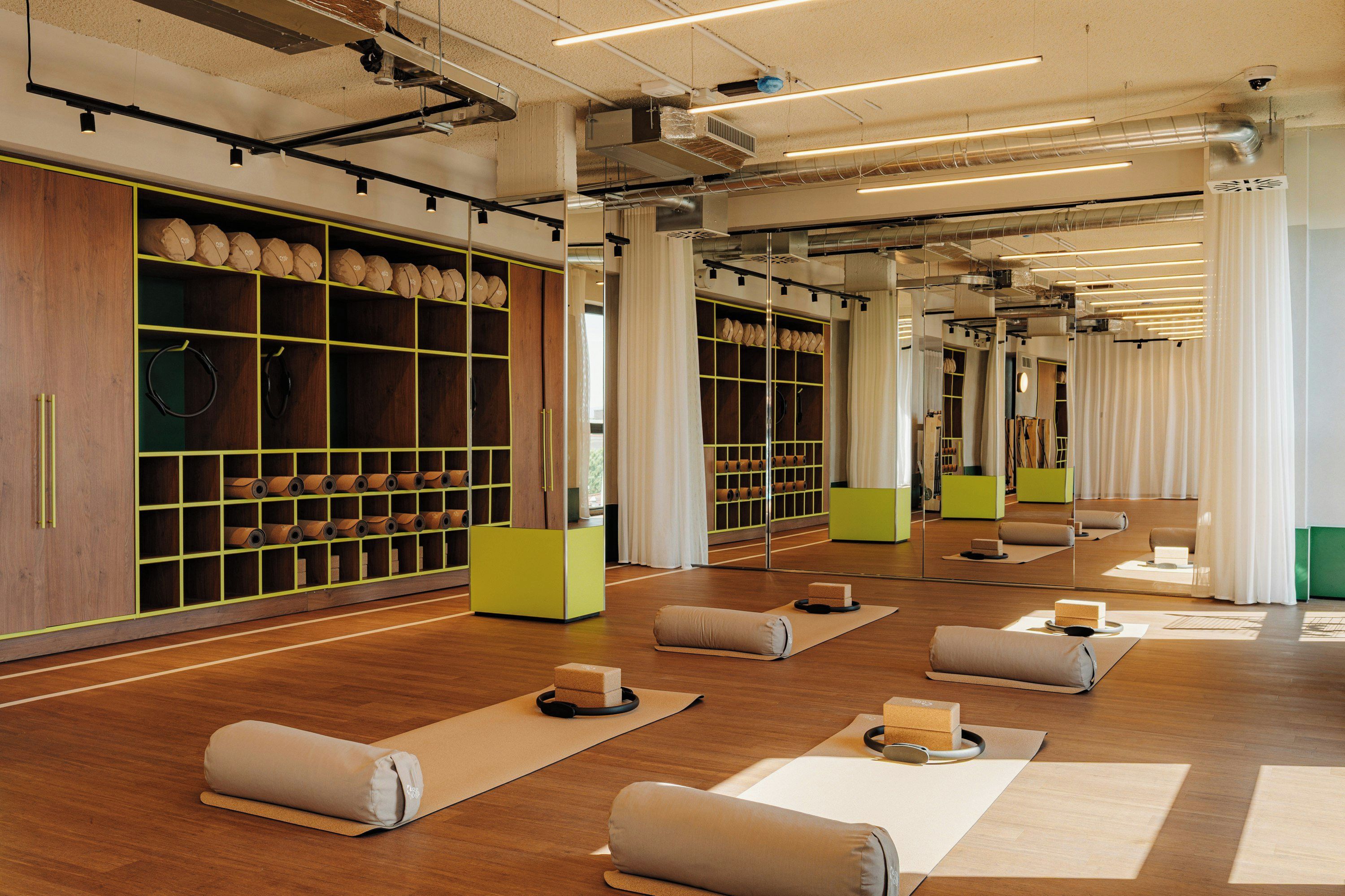 En yogastudio med yogamattor, kuddar och förvaringsmöbler i trä.