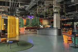 Un interno moderno con una reception, zone relax e piante sospese.