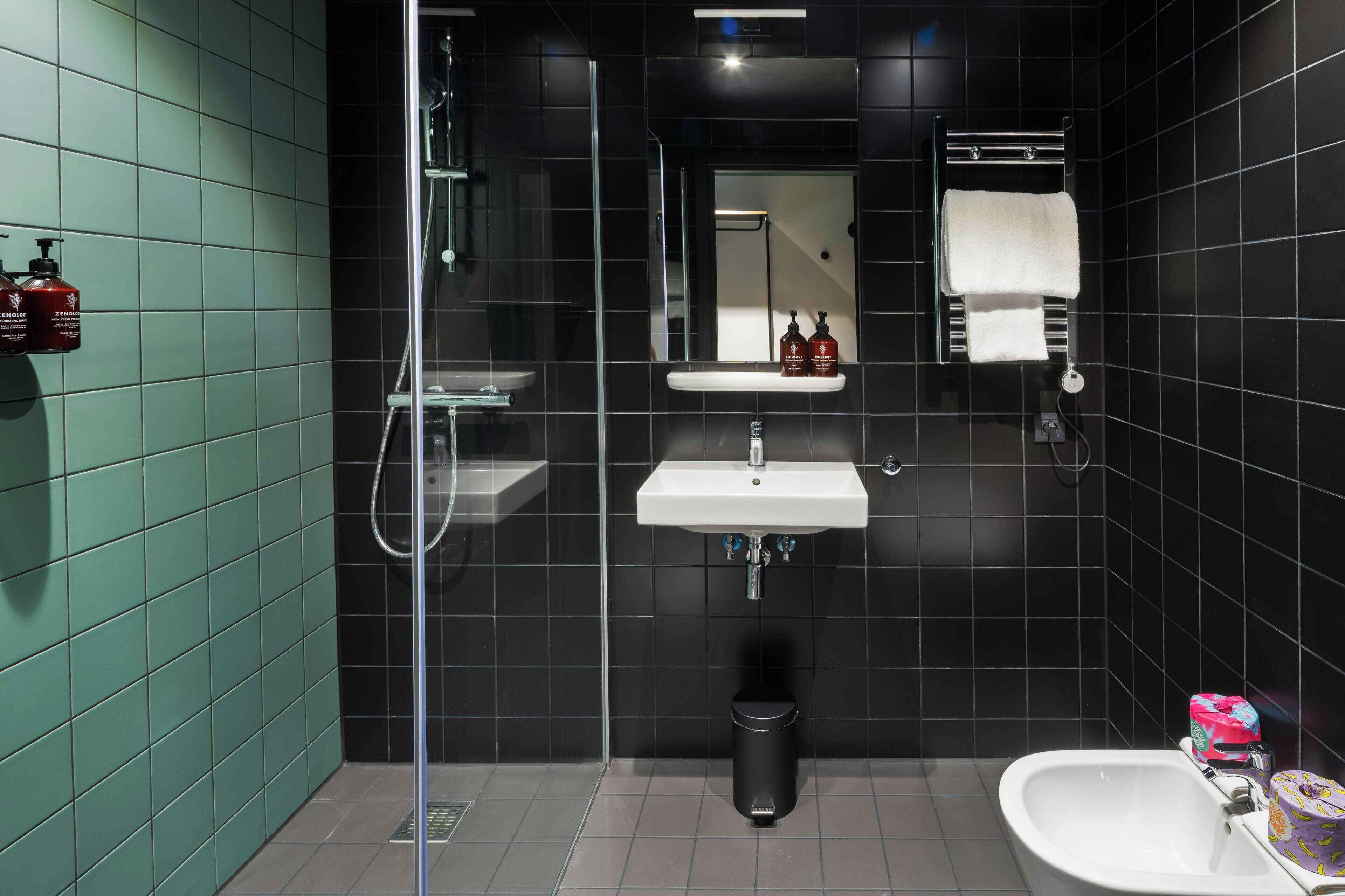 Een moderne badkamer met een glazen douchecabine, een wastafel, een spiegel en een toilet.