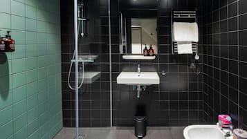 A modern bathroom with a glass shower enclosure, a sink, a mirror, and a bidet.
