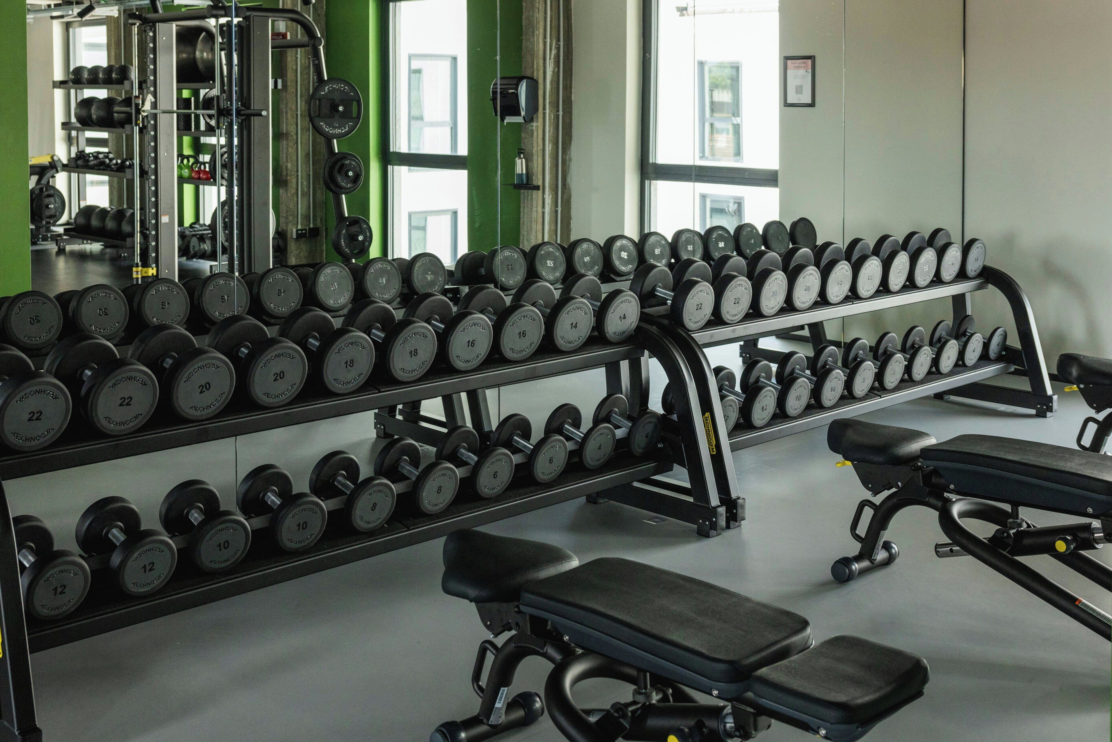 A gym with weightlifting equipment, benches, and dumbbells.