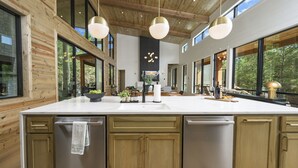 Una cocina moderna con una isla grande, armarios de madera e iluminación colgante.