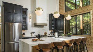 Una cocina moderna con armarios oscuros, electrodomésticos de acero inoxidable y una isla grande con taburetes de bar.