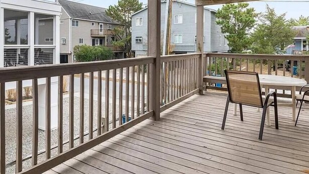 A covered outdoor deck with a railing, a table, and chairs. - Tower Shores Tiny Gem (Bethany Beach)