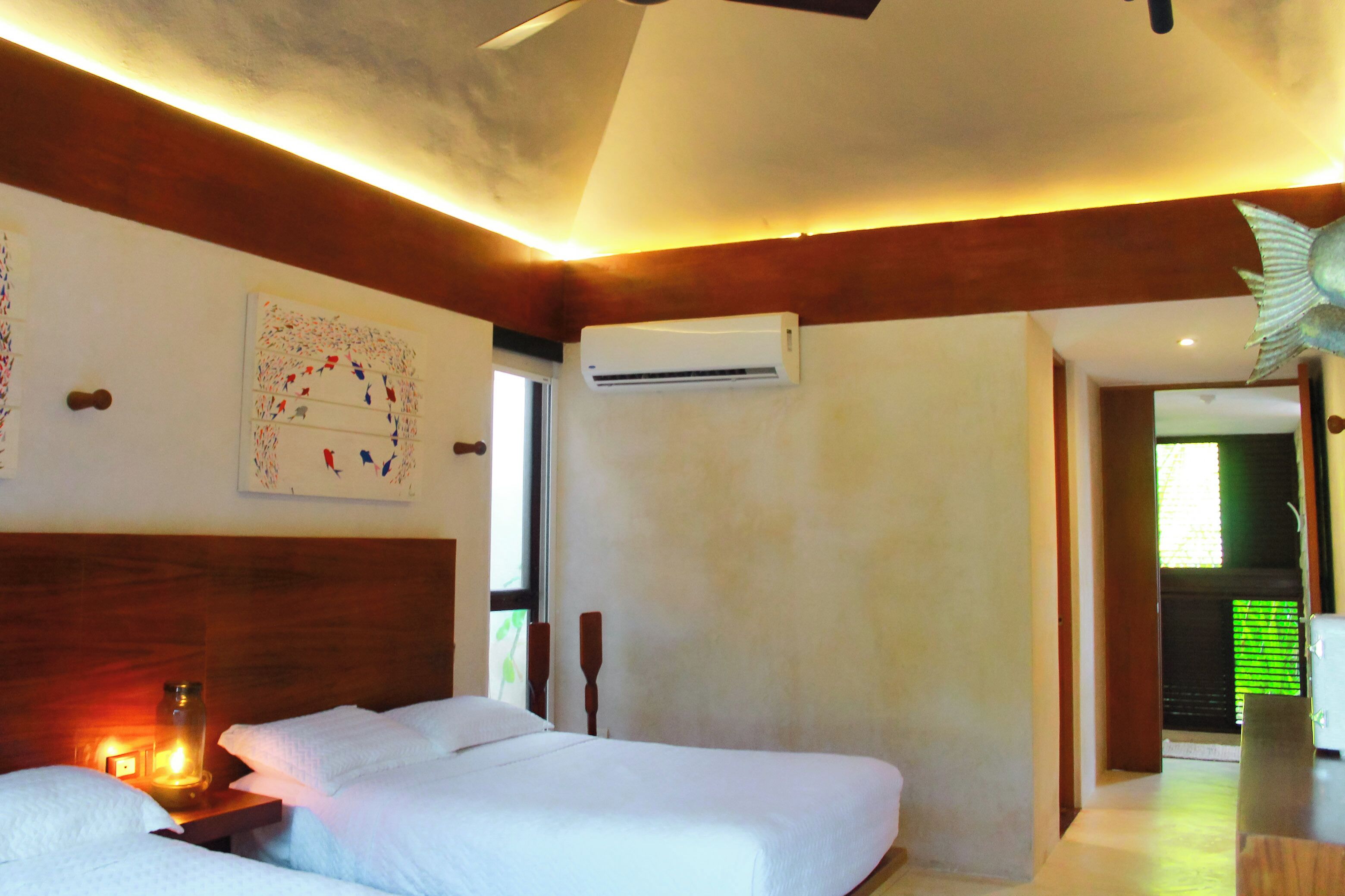 A bedroom with two beds, a wooden headboard, an air conditioning unit, and a decorative wall piece.
