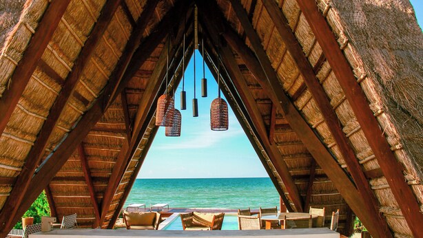 An overwater bungalow with a thatched roof, a pool, and lounge chairs. - Lipsos Retreat Concierge Villa (Ixil)
