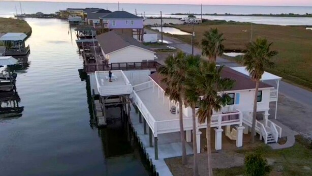 Une propriété située au bord de l’eau, dotée d’un quai, d’une maison avec balcon et de palmiers.