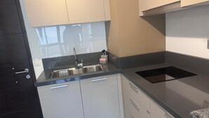 A compact kitchen with a sink, stove, and cabinets. - Painestone apartment (Puerto Natales)