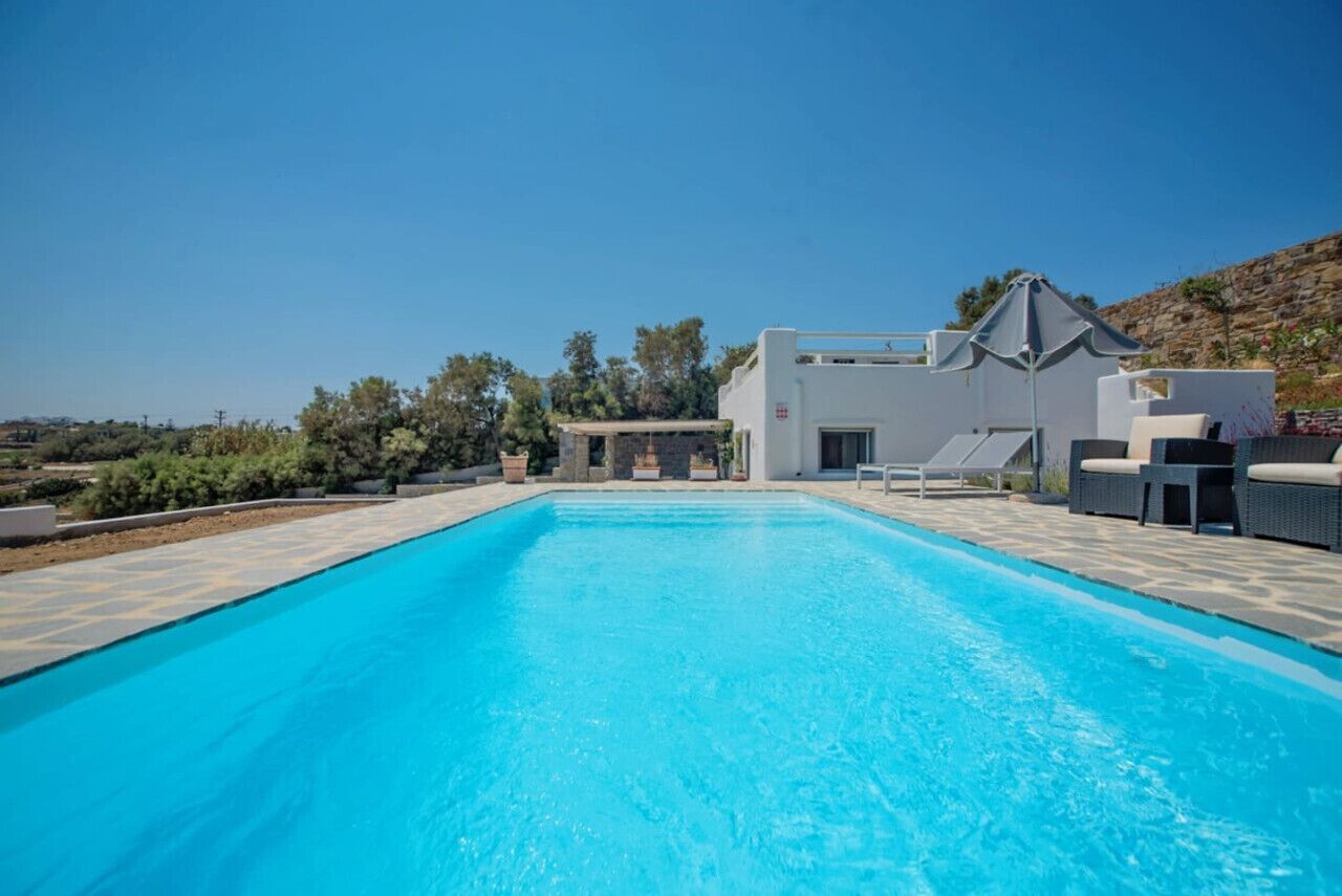 Ein Schwimmbad mit einem modernen Haus im Hintergrund.